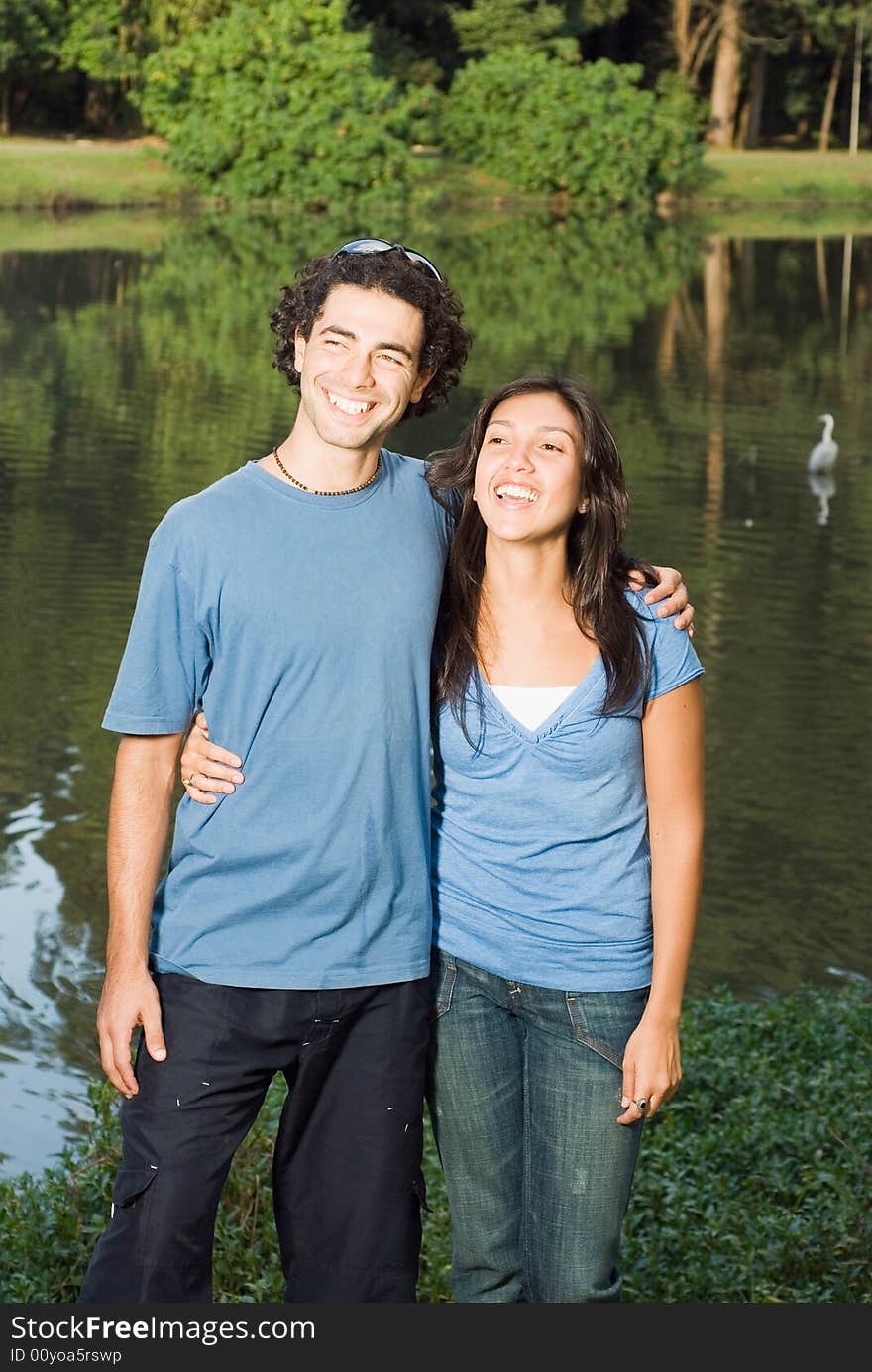 Happy, laughing couple standing in front of a pond. Vertical. Happy, laughing couple standing in front of a pond. Vertical