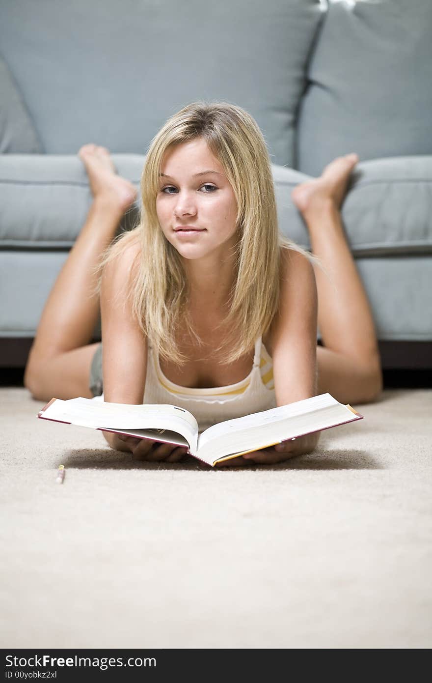 A beautiful young teenage girl reading on the floor. A beautiful young teenage girl reading on the floor