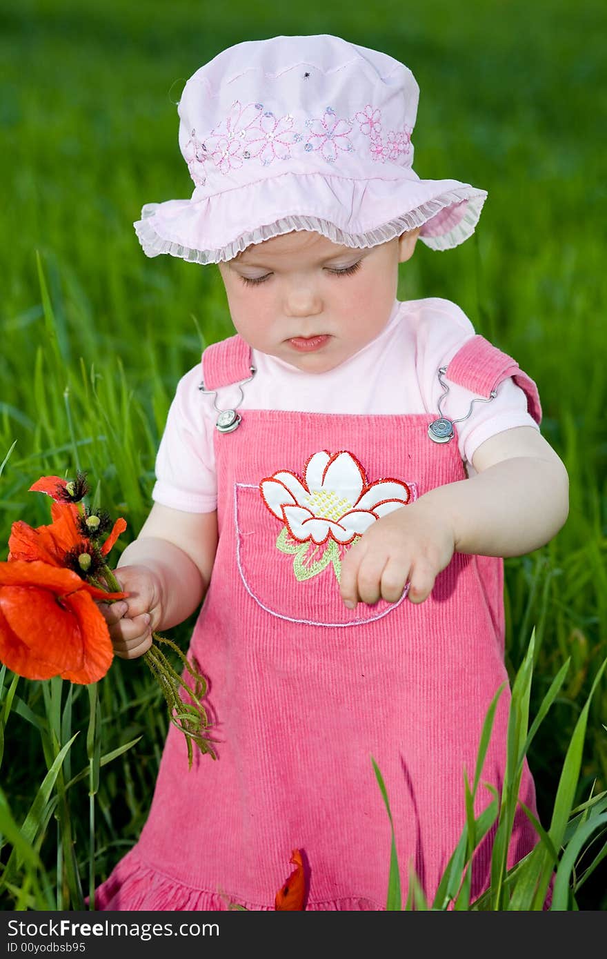 Child with red flower amongst green grass