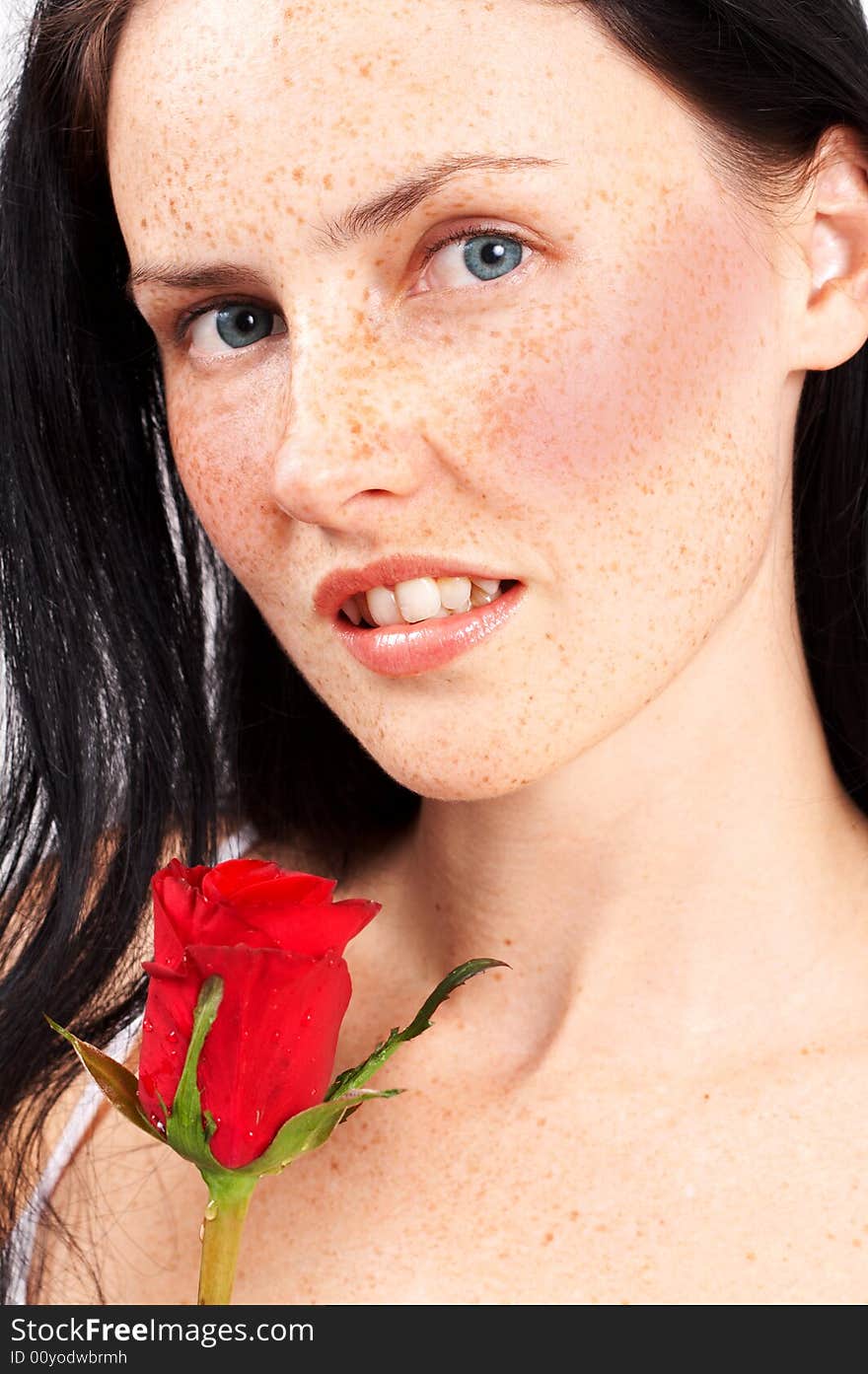 Portrait of a beautiful brunette woman with light grey eyes and freckles on her skin. She is holding a single red rose. Portrait of a beautiful brunette woman with light grey eyes and freckles on her skin. She is holding a single red rose