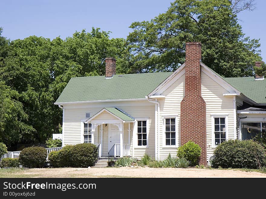 An old farmhouse with a green roof and a brick chimney. An old farmhouse with a green roof and a brick chimney