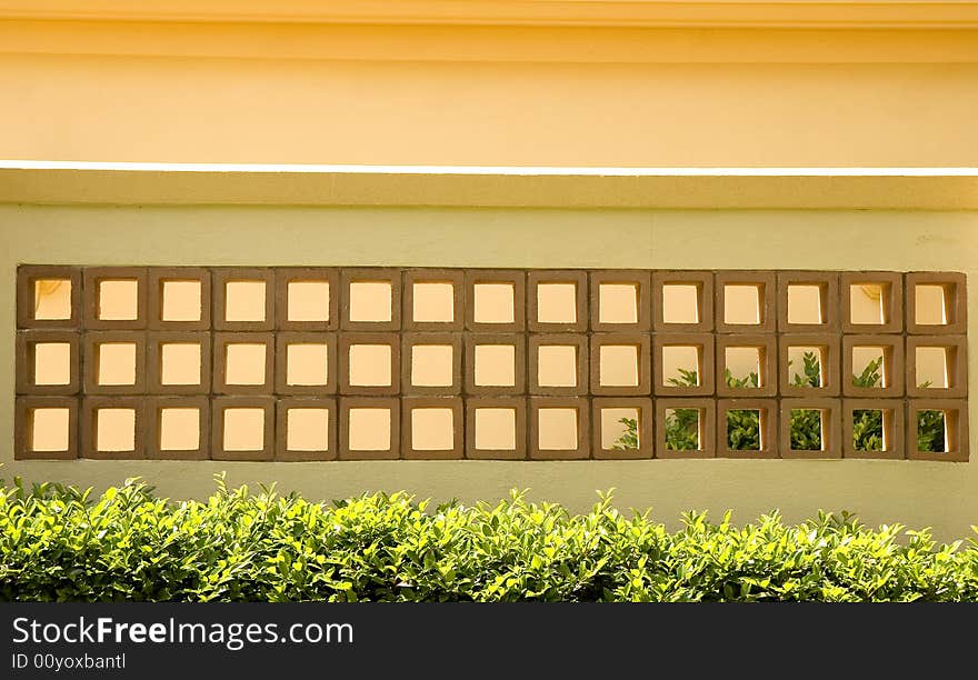 A yellow stucco wall and red tile blocks. A yellow stucco wall and red tile blocks