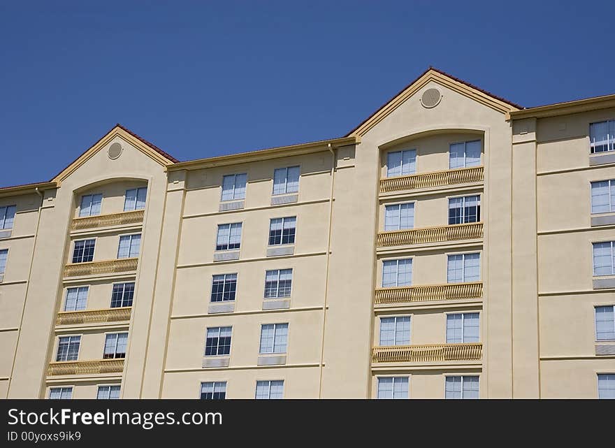 A nice yellow stucco hotel with red roofs against a blue sky. A nice yellow stucco hotel with red roofs against a blue sky