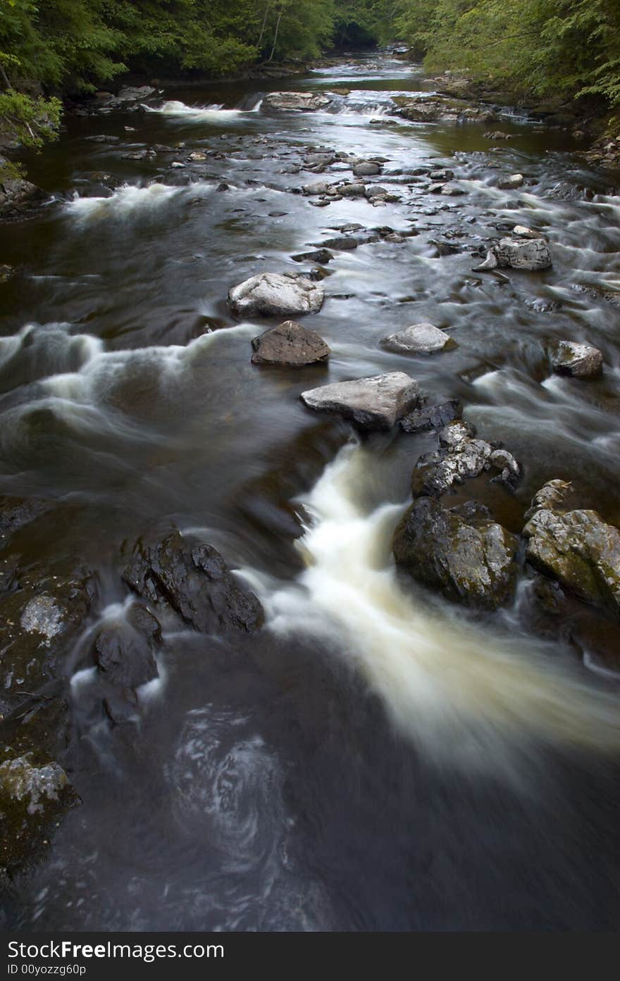 Water stream with the water flowing between rocks.