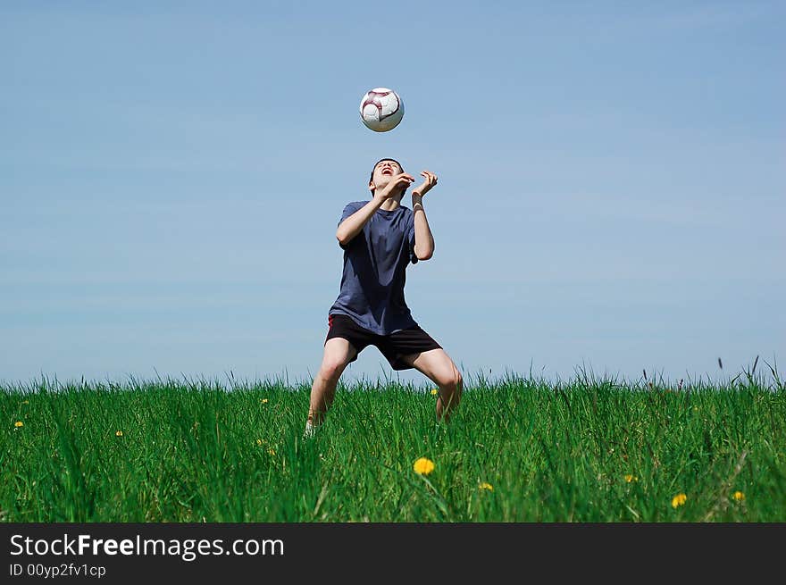 Happy boy playing football on sky background