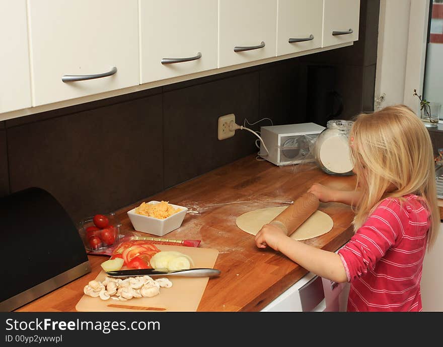 A little girl making pizza at home