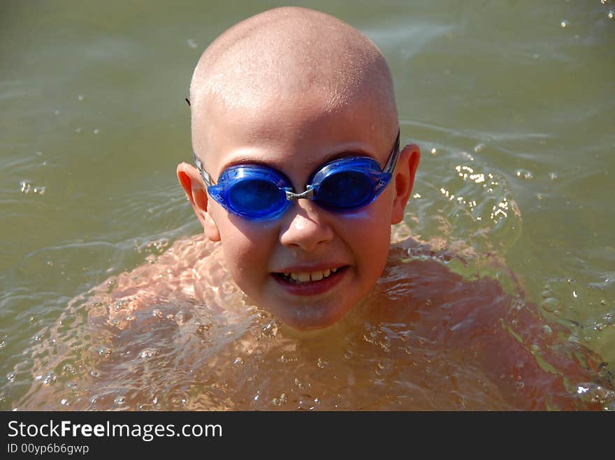 Happy young boy in googles is swimming in the lake