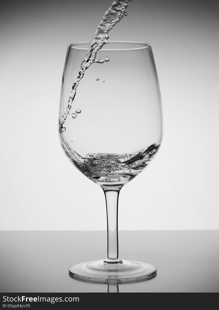 Water being poured into a glass with reflection on white background. Water being poured into a glass with reflection on white background.