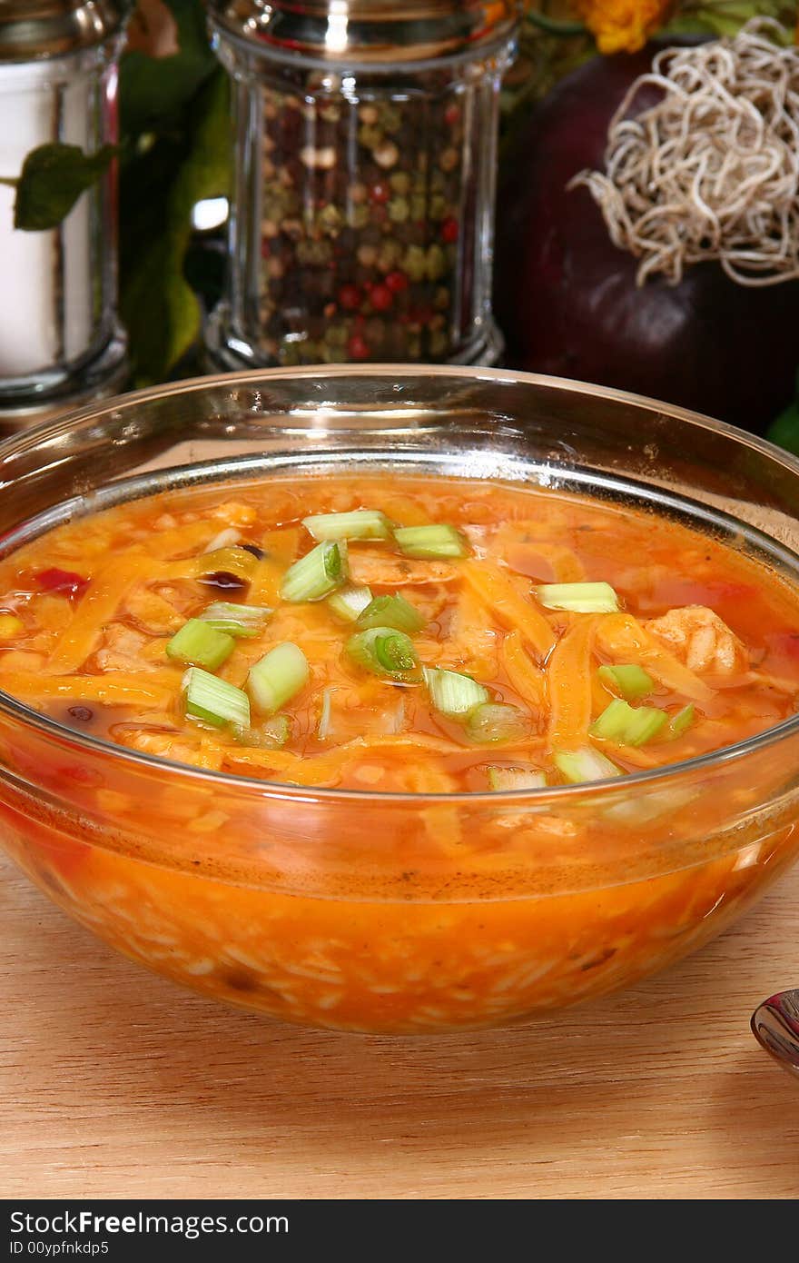 Bowl of Chicken Tortilla Soup garnished with shredded cheddar and green onions.