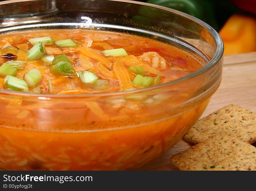 Bowl of Chicken Tortilla Soup garnished with shredded cheddar and green onions.