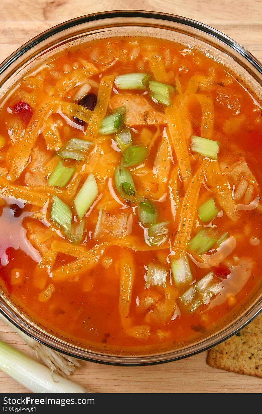 Bowl of Chicken Tortilla Soup garnished with shredded cheddar and green onions.