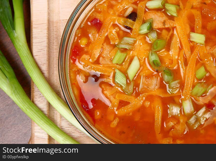 Bowl of Chicken Tortilla Soup garnished with shredded cheddar and green onions.