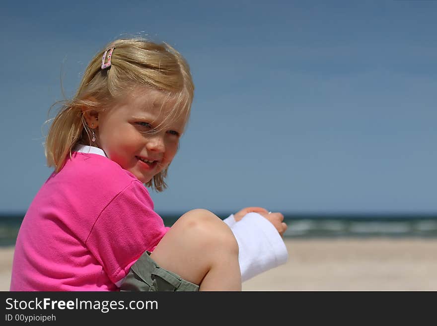 Portrait of little girl sitting  on the  beach over blue sky. Portrait of little girl sitting  on the  beach over blue sky