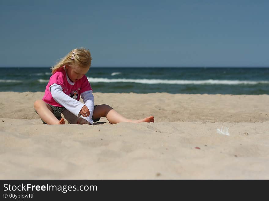 Portrait of little girl sitting  on the  beach over blue sky. Portrait of little girl sitting  on the  beach over blue sky