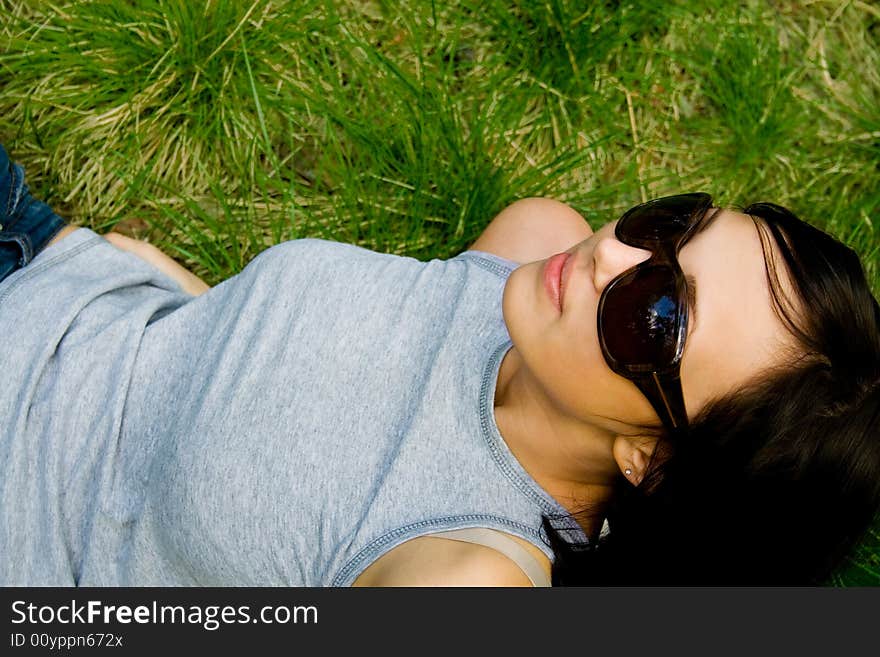 Beautiful young brunet girl lies on green grass. Beautiful young brunet girl lies on green grass