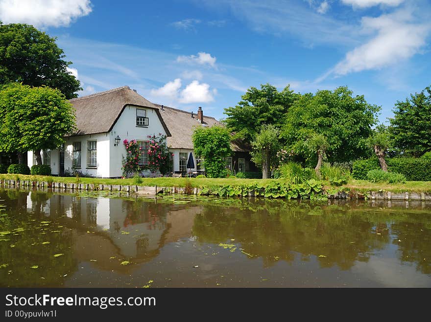 Old farm house with a reflection in the water on a summer day.