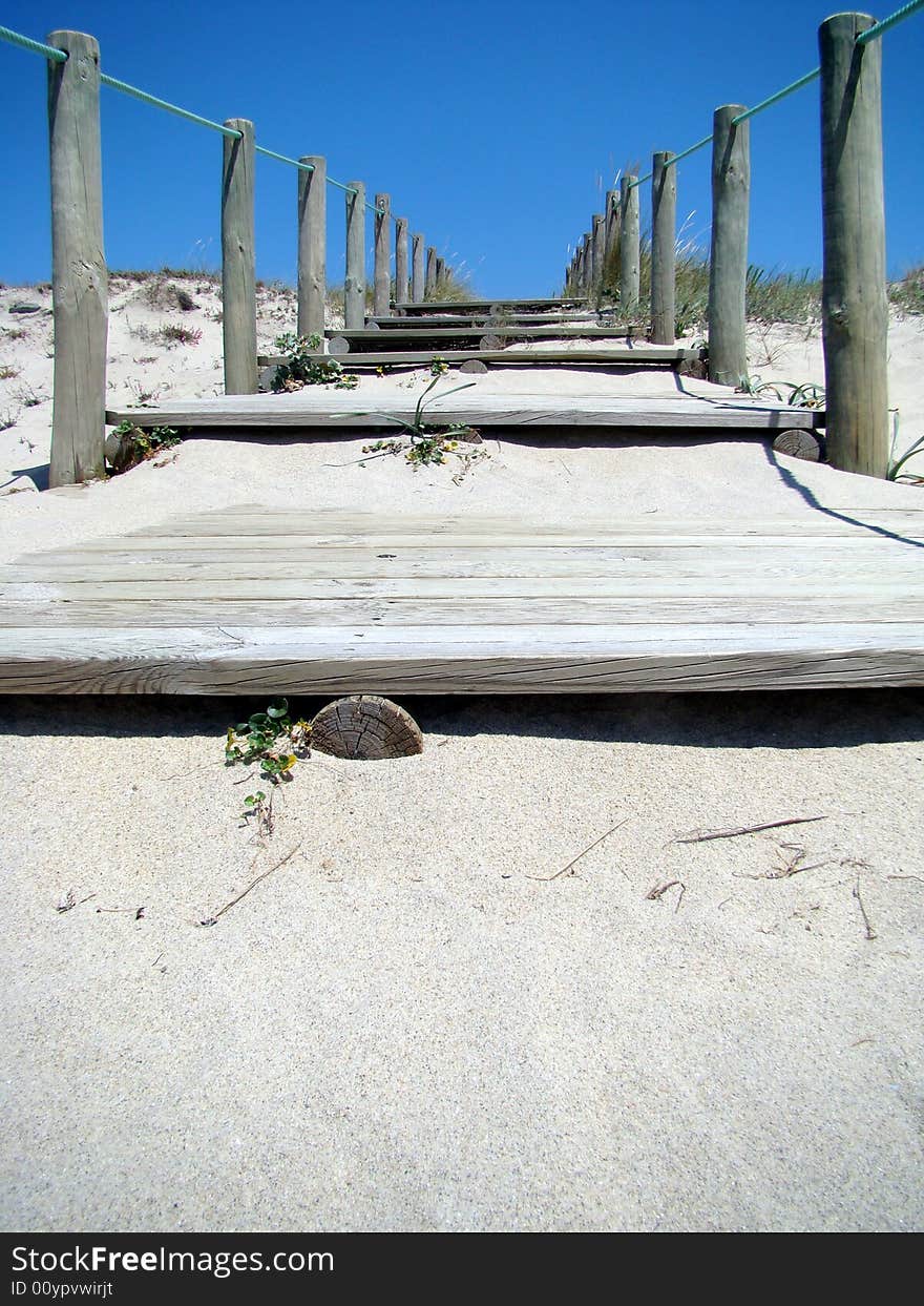 Wooden stairs leading out of beach into the blue sky. Wooden stairs leading out of beach into the blue sky