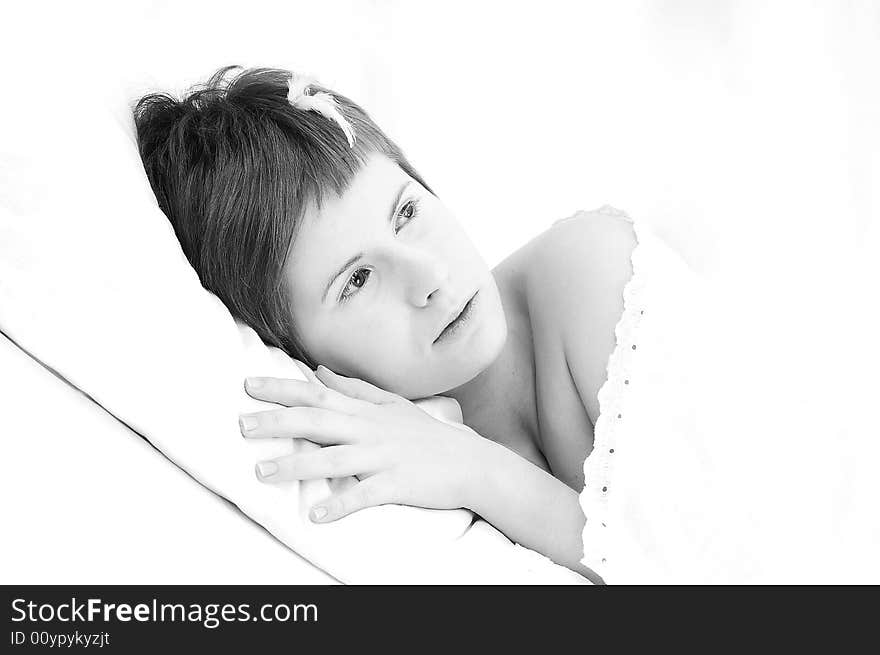 Portrait of short haired girl with white eyelashes and a tiny feather on her head, lying down on a pillow (diagonal composition, high key lightning)