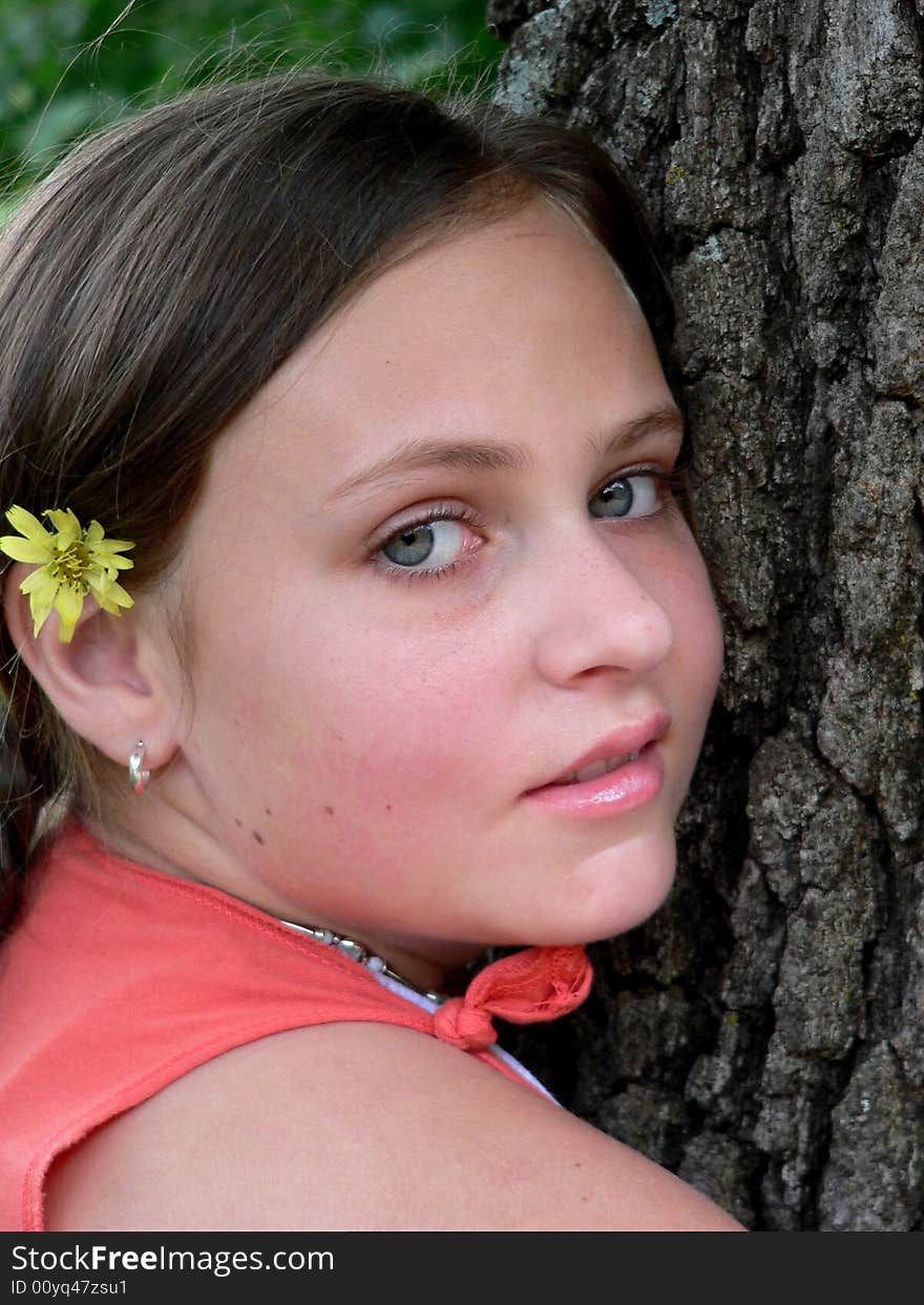 Teenage girl with flower by tree