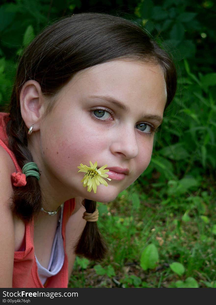 Teenage girl with braids and a yellow flower in her mouth. Teenage girl with braids and a yellow flower in her mouth