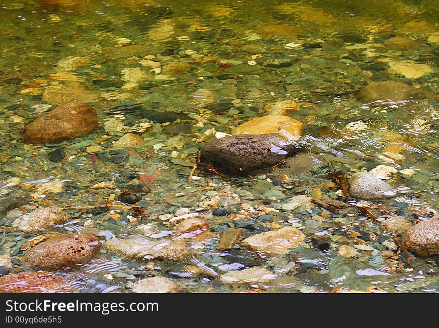 Natural texture. Pure river transparent water with a visible stony bottom - can be used as abstract background. Variant one. Natural texture. Pure river transparent water with a visible stony bottom - can be used as abstract background. Variant one.