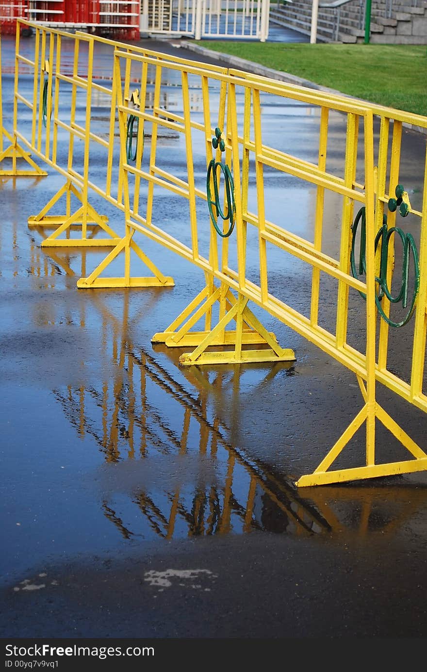 Bright yellow crowd control fence with reflection after rain. Bright yellow crowd control fence with reflection after rain