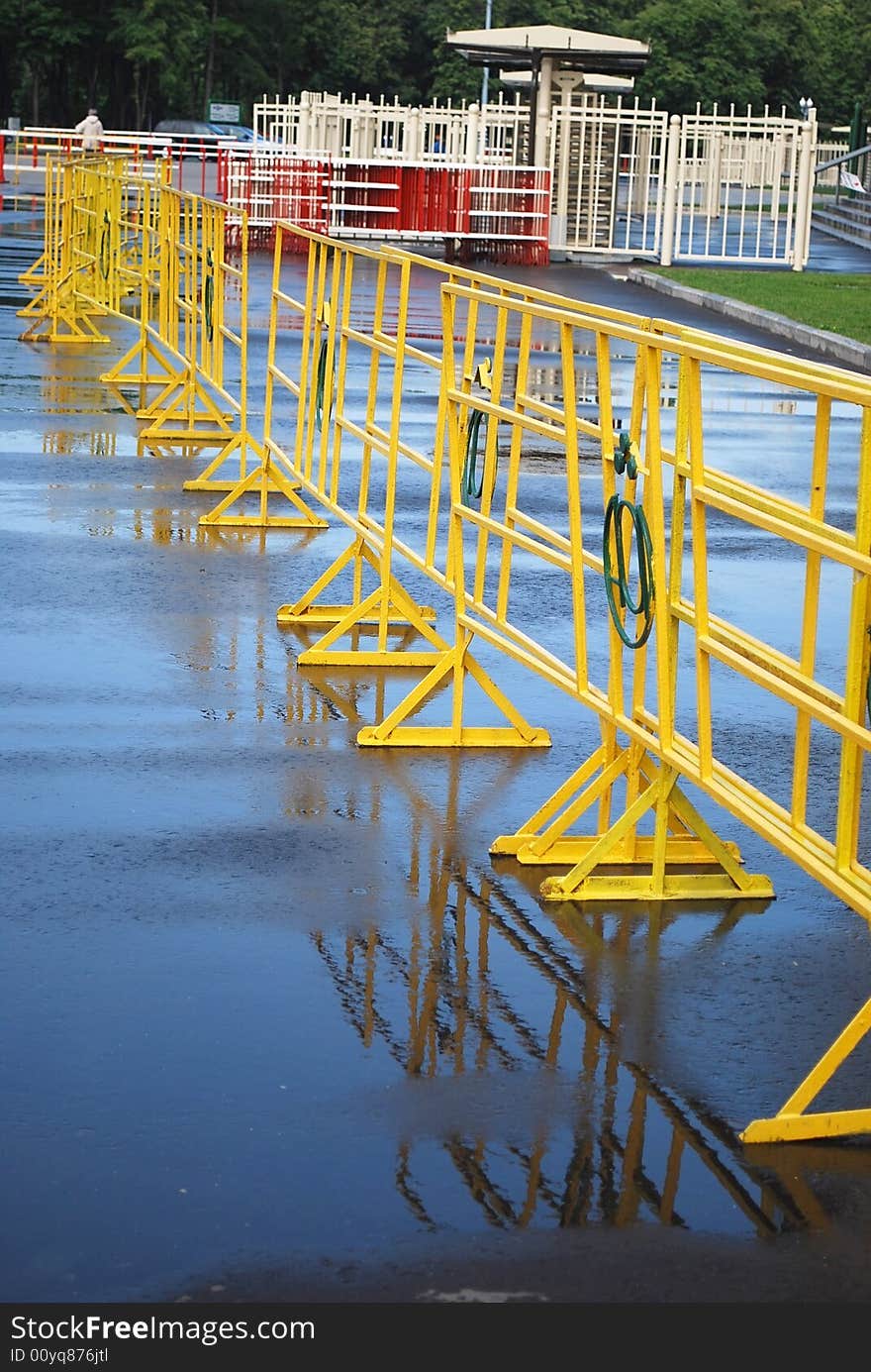 Bright yellow crowd control fence with reflection after rain. Bright yellow crowd control fence with reflection after rain