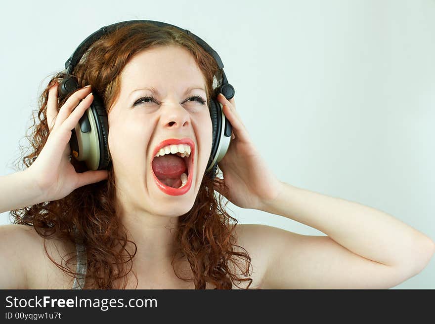 The girl in headphones shouts on a white background. The girl in headphones shouts on a white background