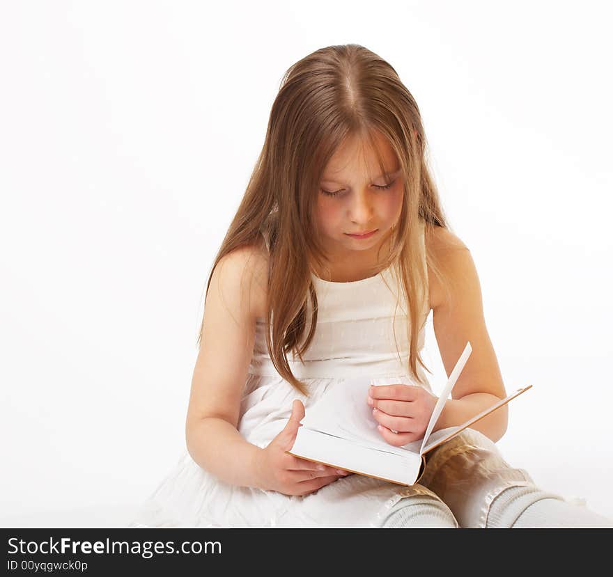 The little girl with long hair sits and reads the book. The little girl with long hair sits and reads the book