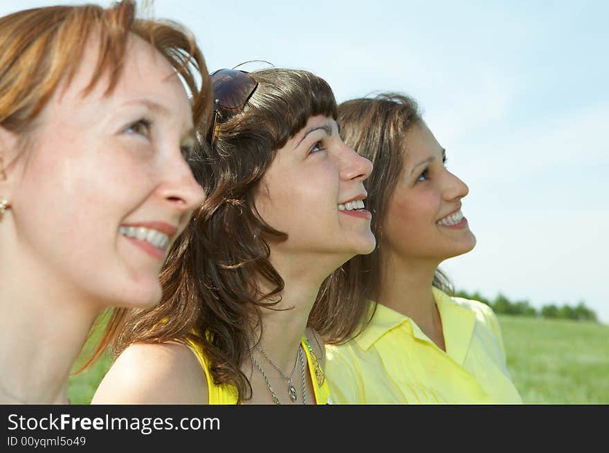 Three girlfriend in green field under blue sky