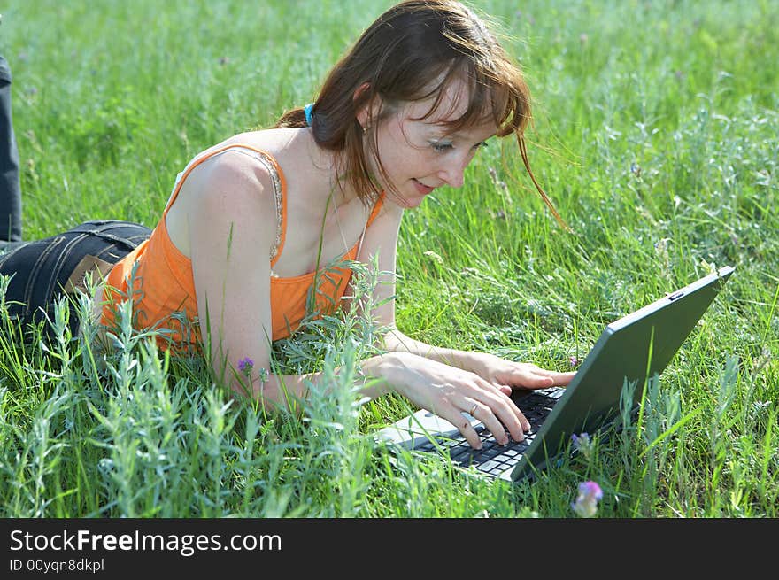 Pretty woman with laptop on the green grass