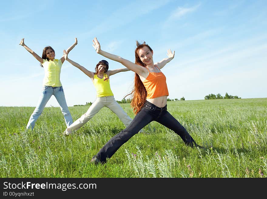 Three girlfriend in green field under blue sky