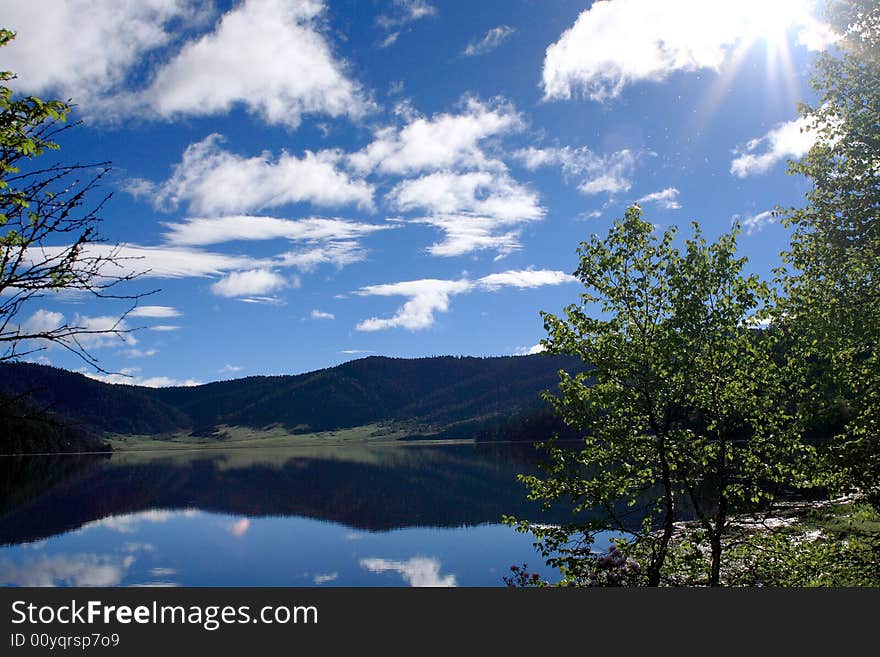 Lake in mountains surrounded by  woods and the cloudy sky above it. Lake in mountains surrounded by  woods and the cloudy sky above it.