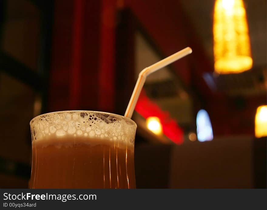 Froth on the cup of coffee in a clear glass (dark cafe background)