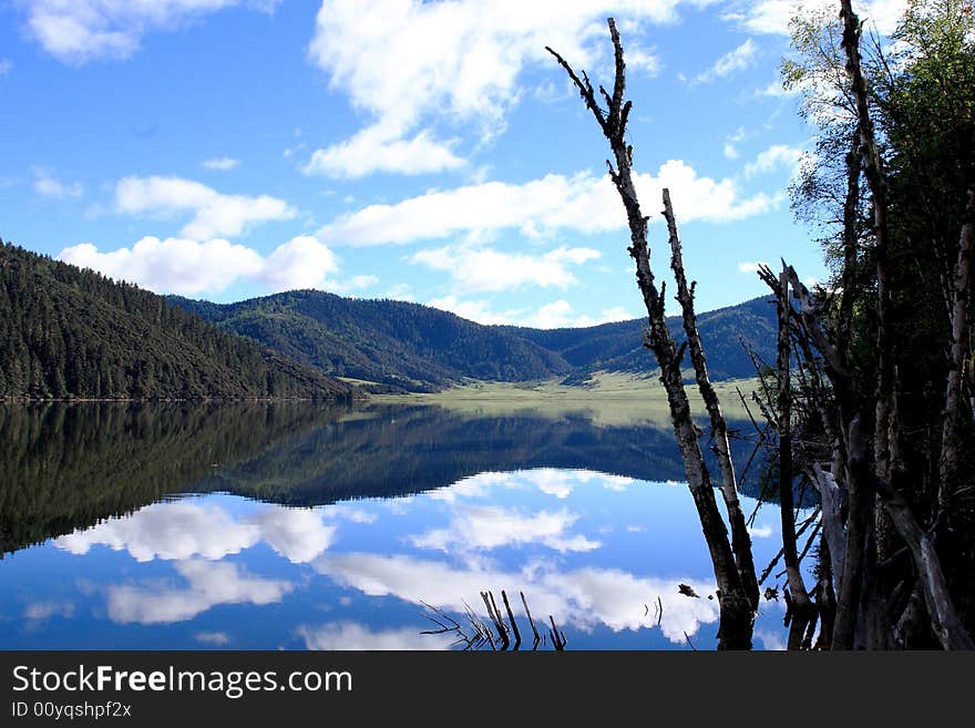 Lake in mountains surrounded by  woods and the cloudy sky above it. Lake in mountains surrounded by  woods and the cloudy sky above it.