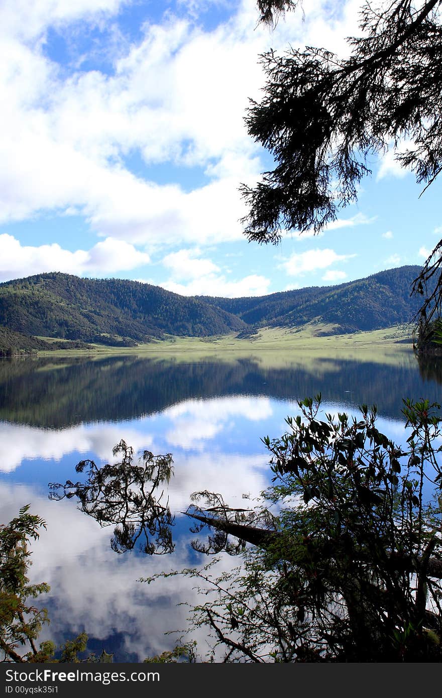 Lake in mountains surrounded by  woods and the cloudy sky above it. Lake in mountains surrounded by  woods and the cloudy sky above it.