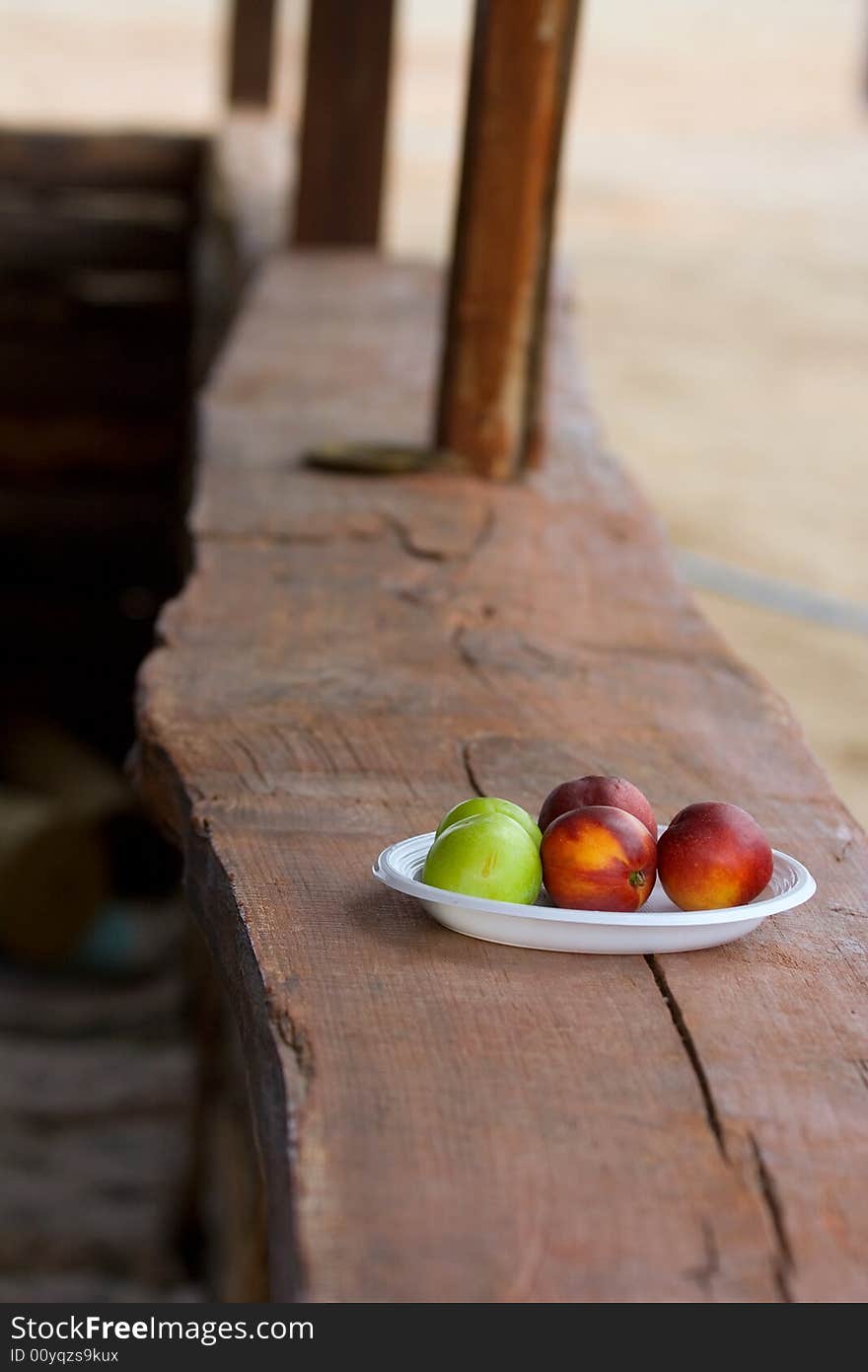 The red and green peaches in the plastic dish. The red and green peaches in the plastic dish.