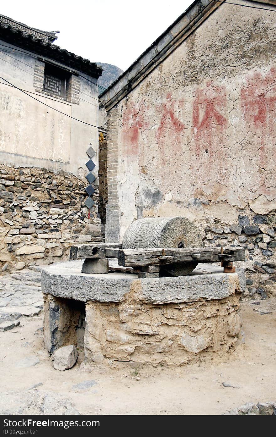 Stone mill in the ancient village. 
It has already been a historical relic here now. 

Chinese characters on the wall are slogans of the Culture Revolution in the same year. Mean and study, study again.