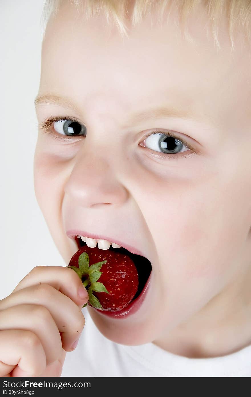 A small boy eating  strawberry