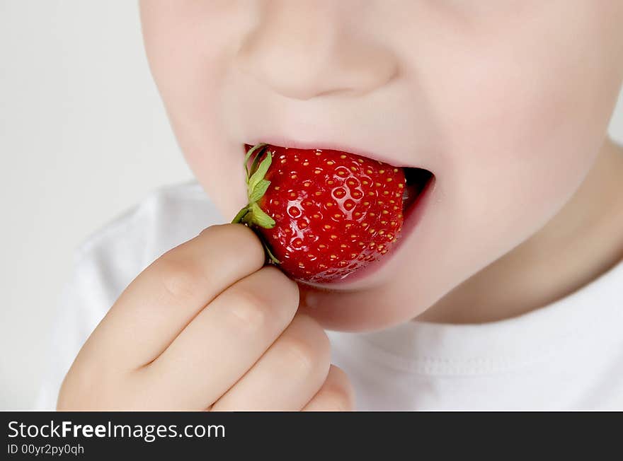 A small boy eating  strawberry