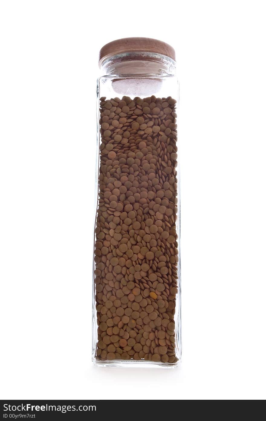 Glass storage bottle containing fresh lentils in a white background. Glass storage bottle containing fresh lentils in a white background