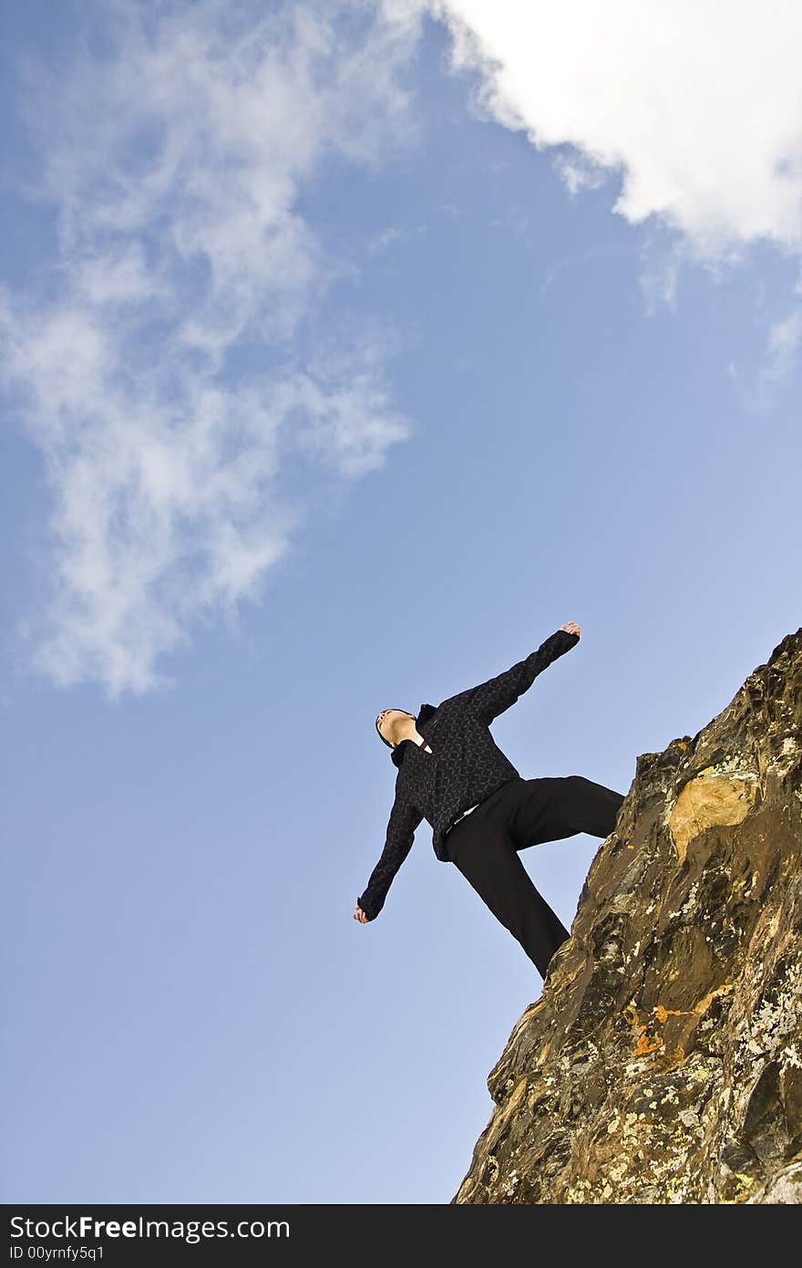 Young man on the rocks in defiant gesture. Young man on the rocks in defiant gesture