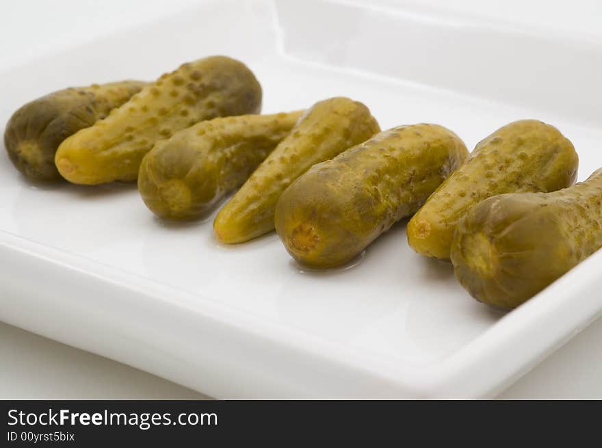 Fresh dill pickles on plate, isolated, studio shot.