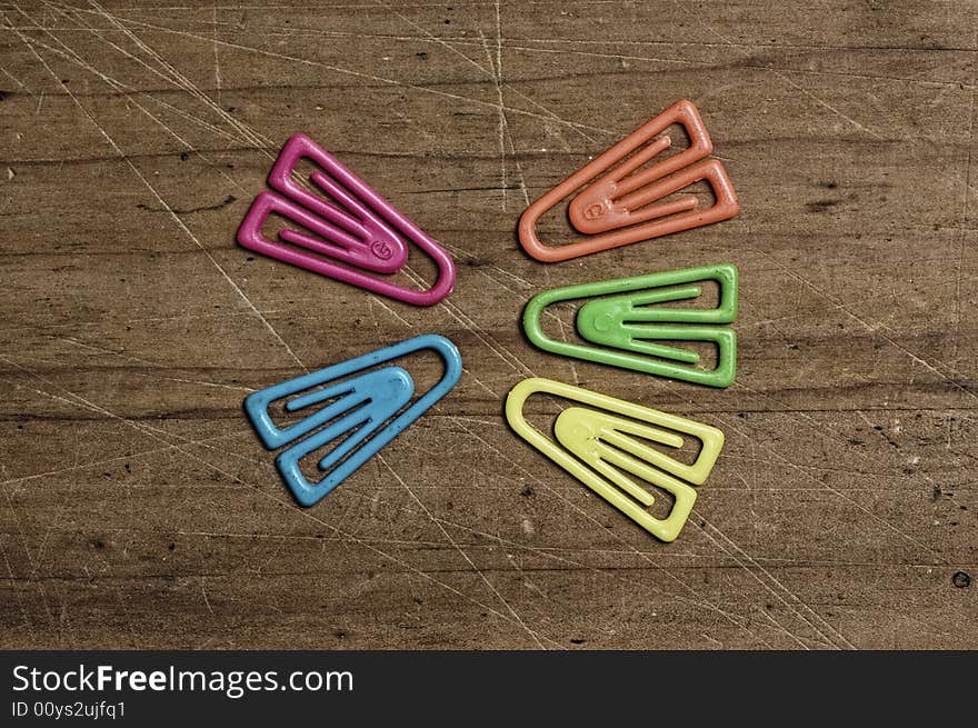 Color paper clips on wooden table.