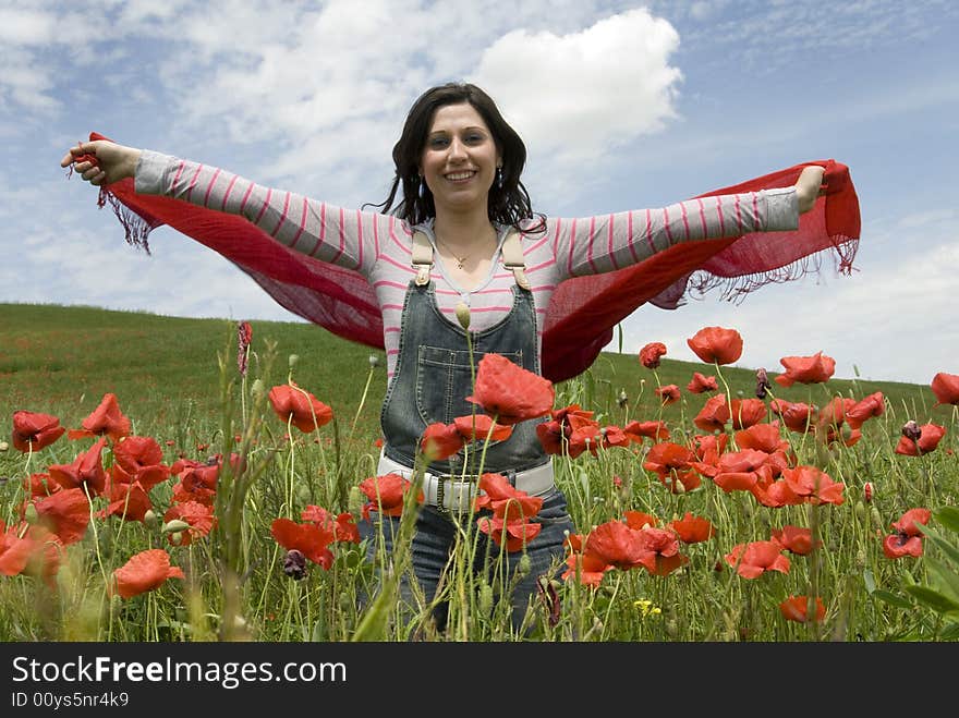 Beautiful girl standing among red poppies and holding a red scarf. Beautiful girl standing among red poppies and holding a red scarf