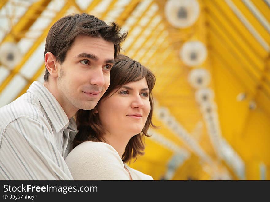 Boy embraces girl from back on  yellow footbridge