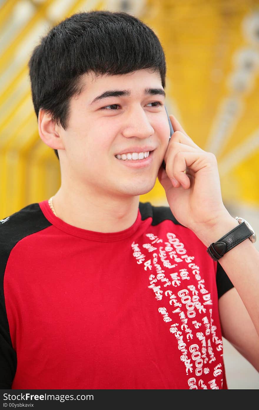 Young man talks by cell phone on yellow footbridge. Young man talks by cell phone on yellow footbridge