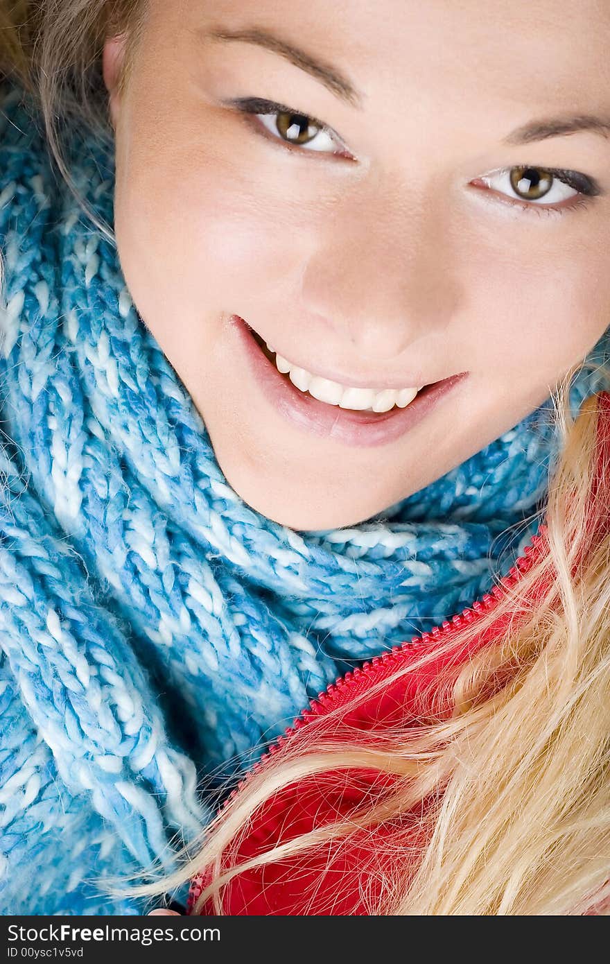 Smiling young woman wearing red jacket and blue scarf. Autumn or winter fashion. Smiling young woman wearing red jacket and blue scarf. Autumn or winter fashion.