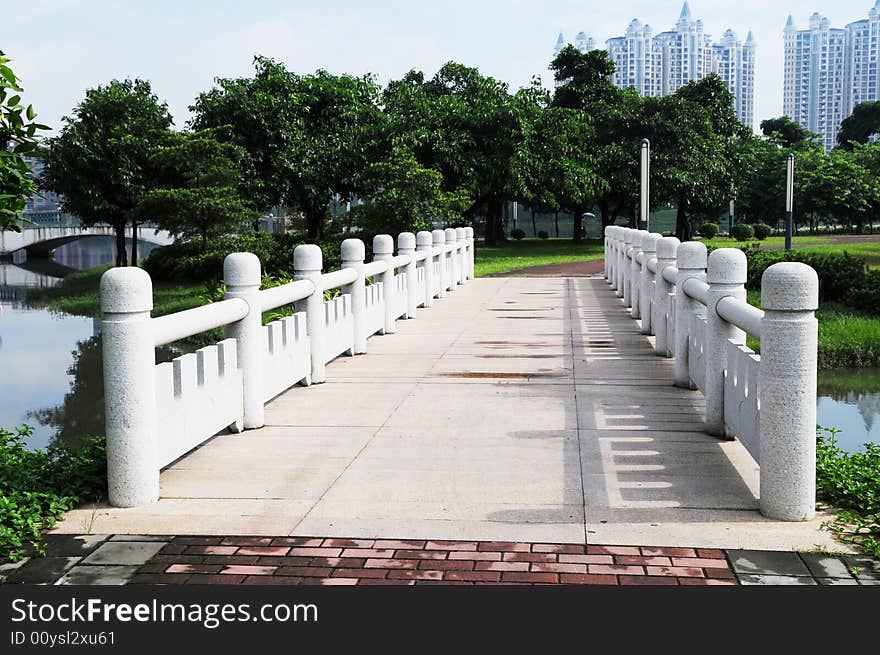 The bricked stone bridge with railings in a Chinese city park.