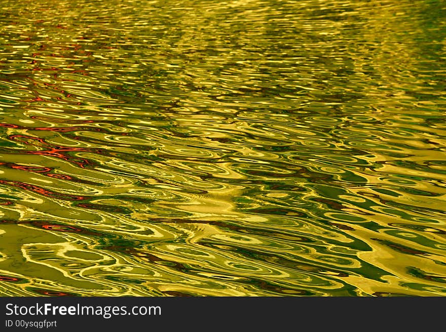 The golden water ripples in a small river. The golden water ripples in a small river.